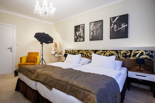 A hotel room with a large bed, a desk, a chair, and a chandelier.