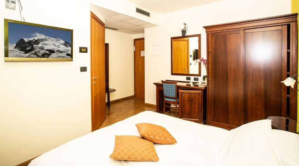 Una habitación de hotel con cama, escritorio, armario y baño.