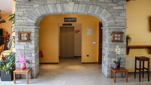 A stone archway leading to a room with a wooden ceiling, a potted plant, and a small table. - Crabun (Pont-Saint-Martin)