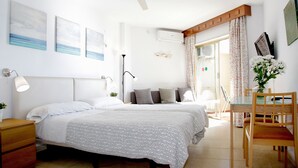 Une chambre avec deux lits, un ventilateur de plafond, une table de chevet avec une lampe et une fenêtre avec des rideaux.