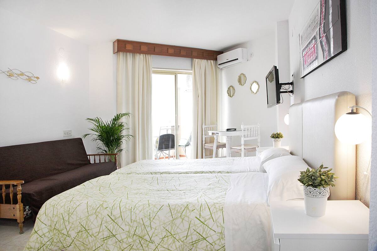 Hotellihuone, jossa on sänky, sohva, työpöytä ja tuoli.