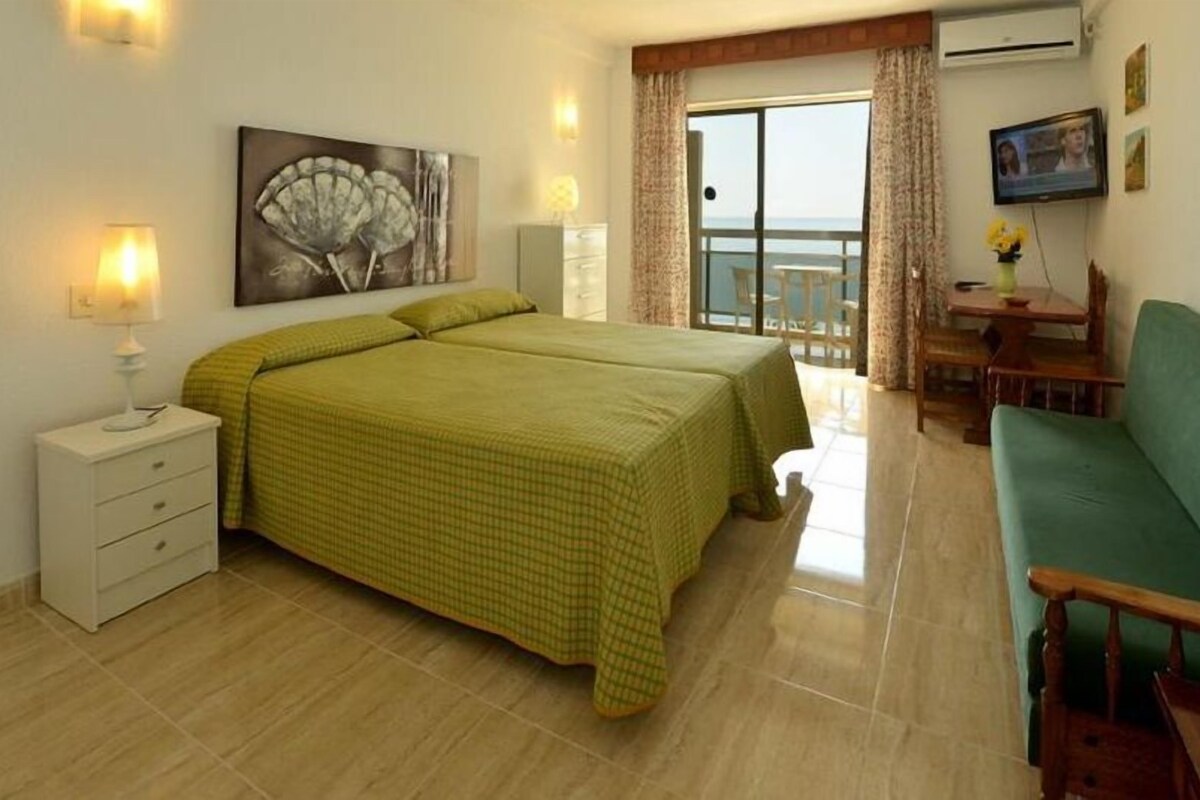 A hotel room with a bed, a sofa, a desk, and a balcony.