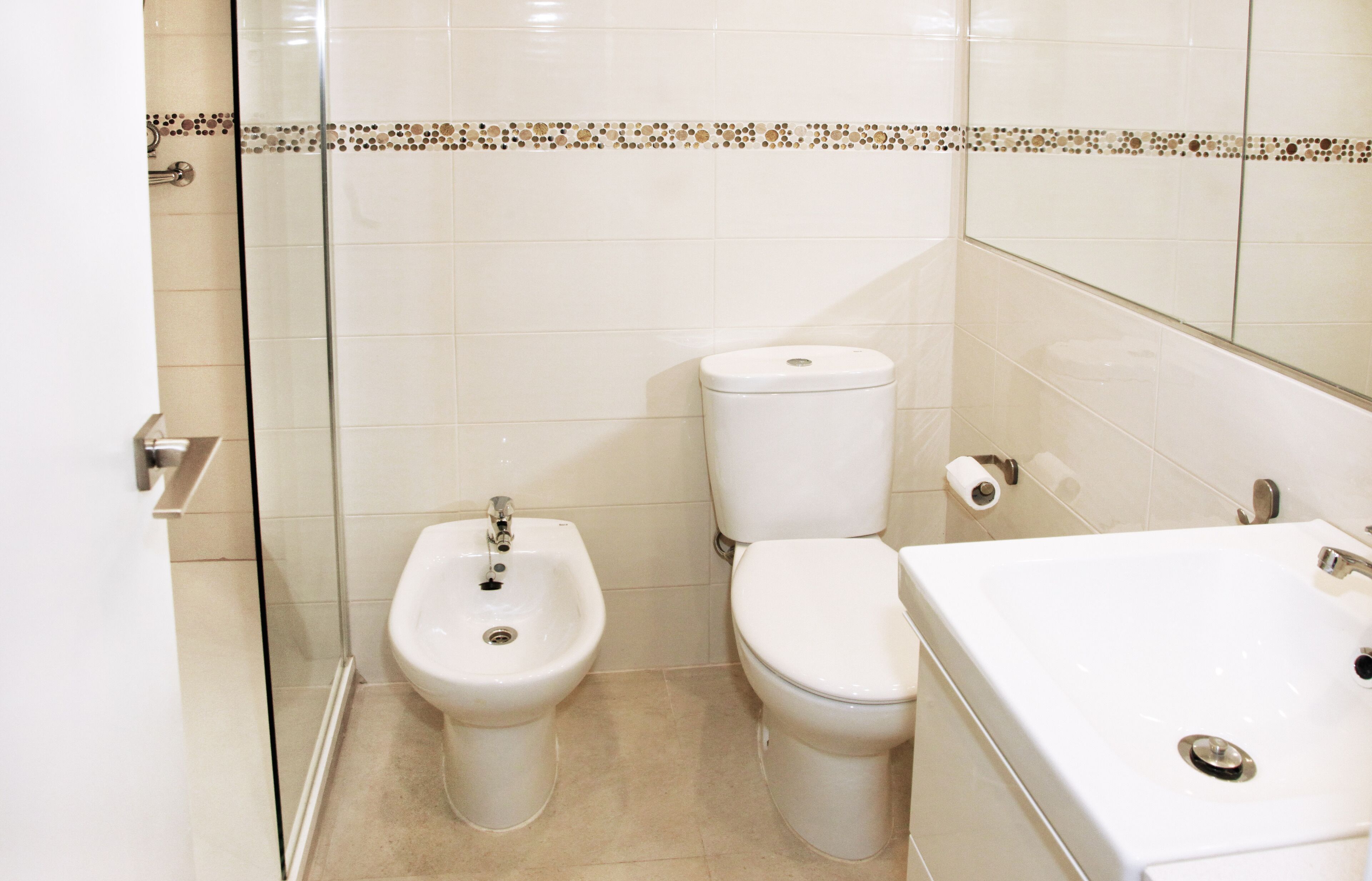 A bathroom with a bidet, toilet, and sink.