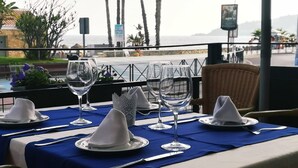 Une table dressée pour le dîner, avec vue sur la mer et les palmiers.