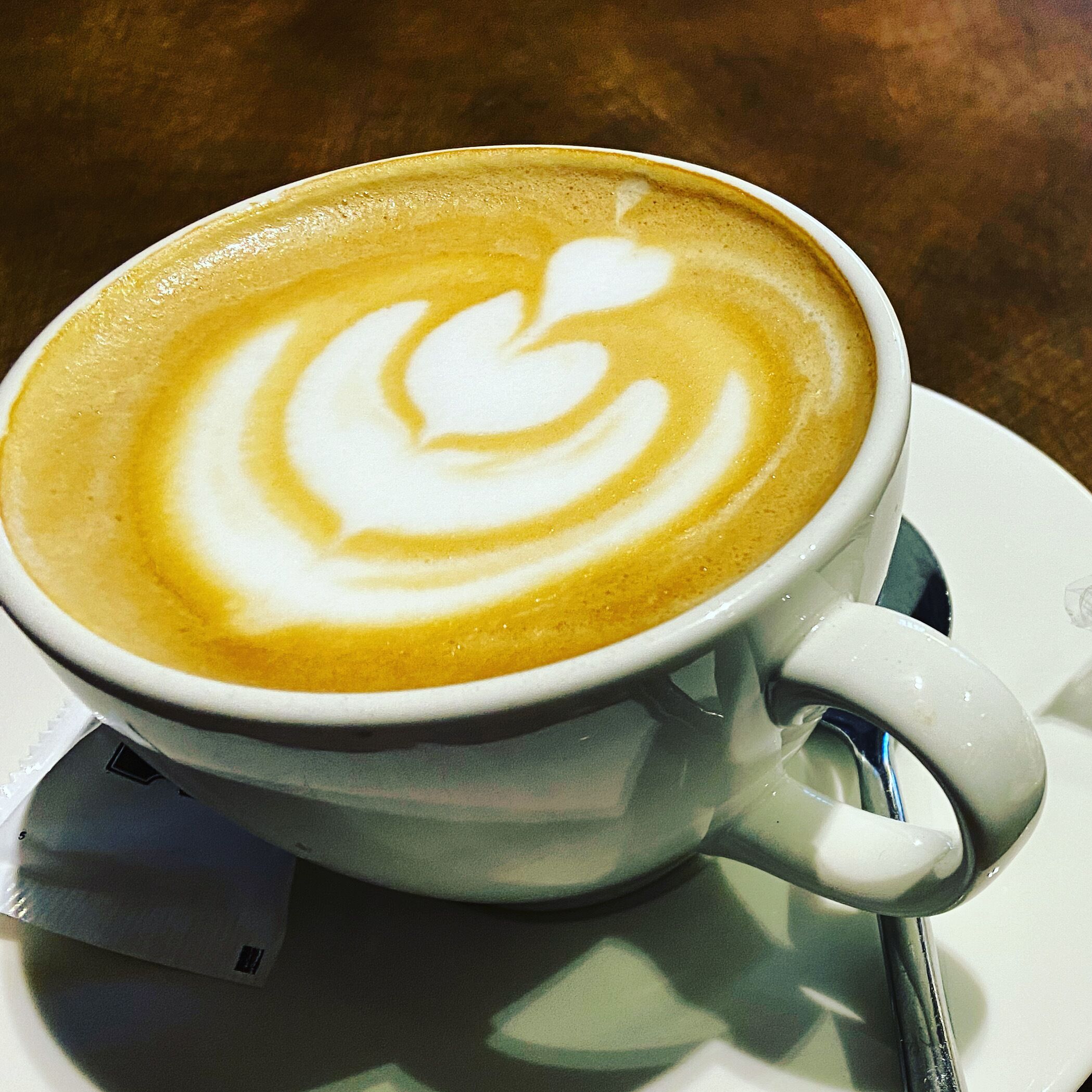 Una taza de café con un diseño artístico en el plato.