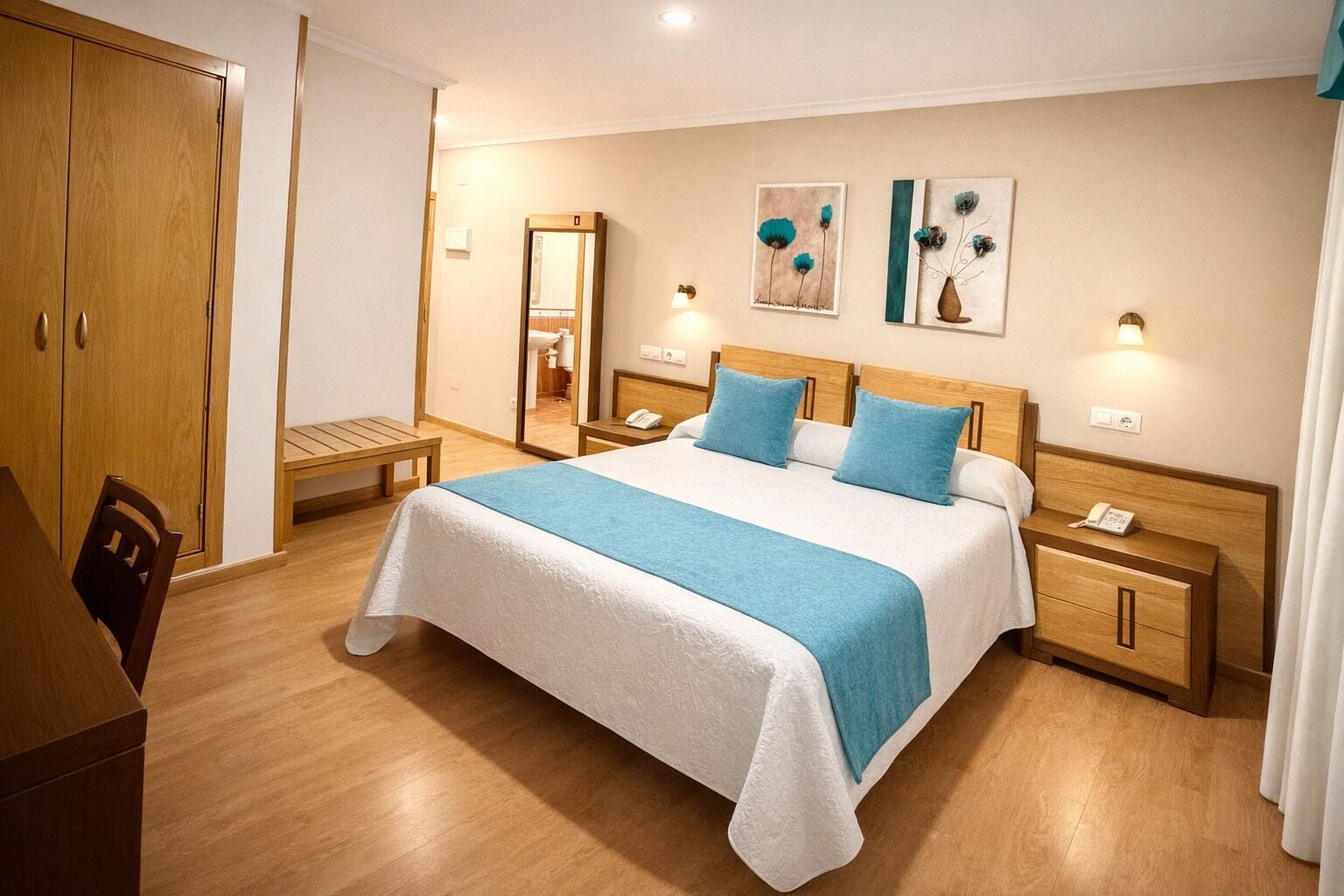 Een hotelkamer met een bed, nachtkastjes, een kledingkast en kunst aan de muur.