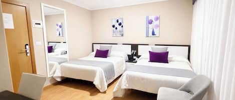 A hotel room with two beds, a desk, a chair, and artwork on the walls.