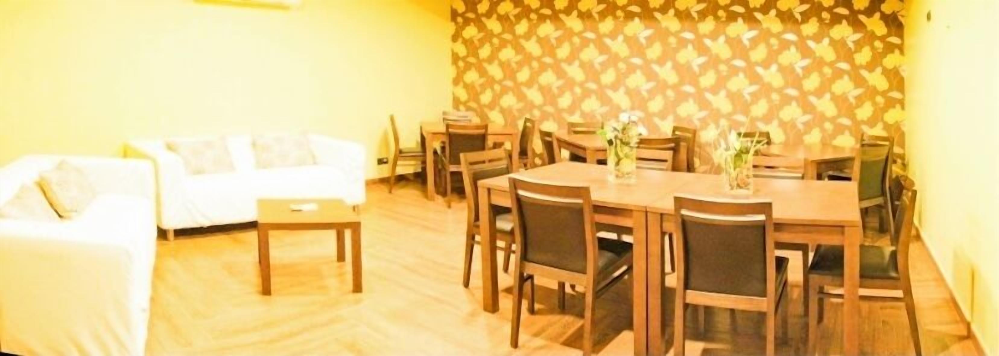 A dining area with a wooden table and chairs, a white sofa, and a patterned wall.