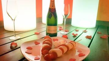 A bottle of Moët & Chandon champagne, a plate with skewers of strawberries and cream, and two empty wine glasses on a wooden table.