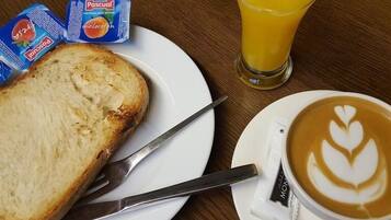 A breakfast setting with toast, Pascal milk, juice, and a latte with latte art.