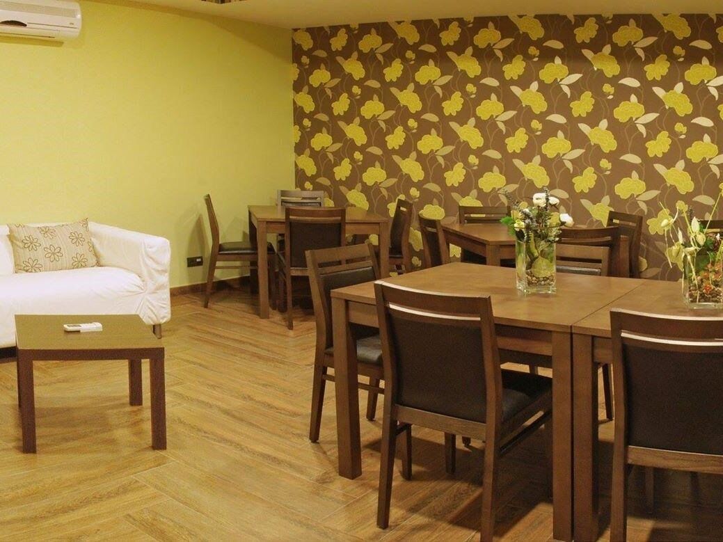 Een eetgedeelte met een houten tafel en stoelen, een witte bank en behang met bloemen.