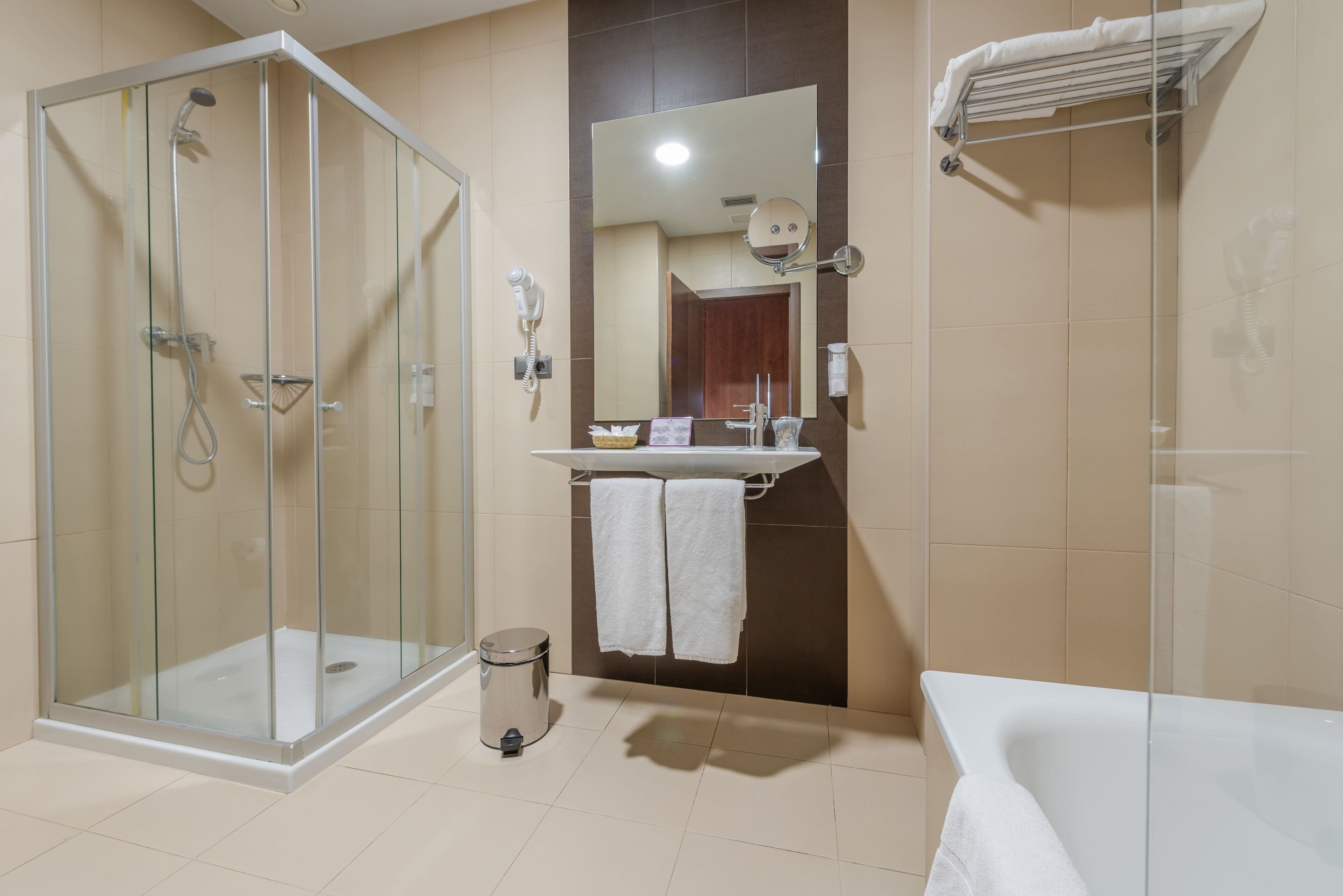 Un baño moderno con ducha de vidrio, lavamanos con espejo y bañera.
