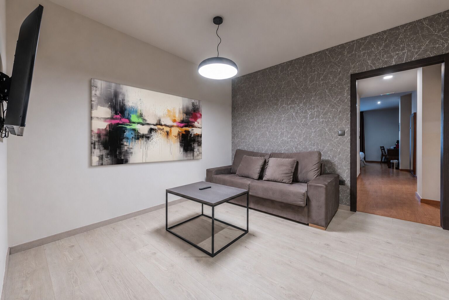 Ein modernes Wohnzimmer mit einer Couch, einem Couchtisch und einem abstrakten Gemälde.