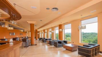 Un lobby espacioso con una recepción, zona de estar y ventanas amplias que ofrecen vistas al exterior.