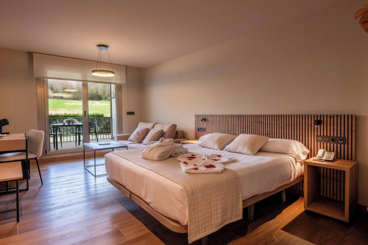 Un dormitorio con cama, mesita de noche y vistas al exterior.