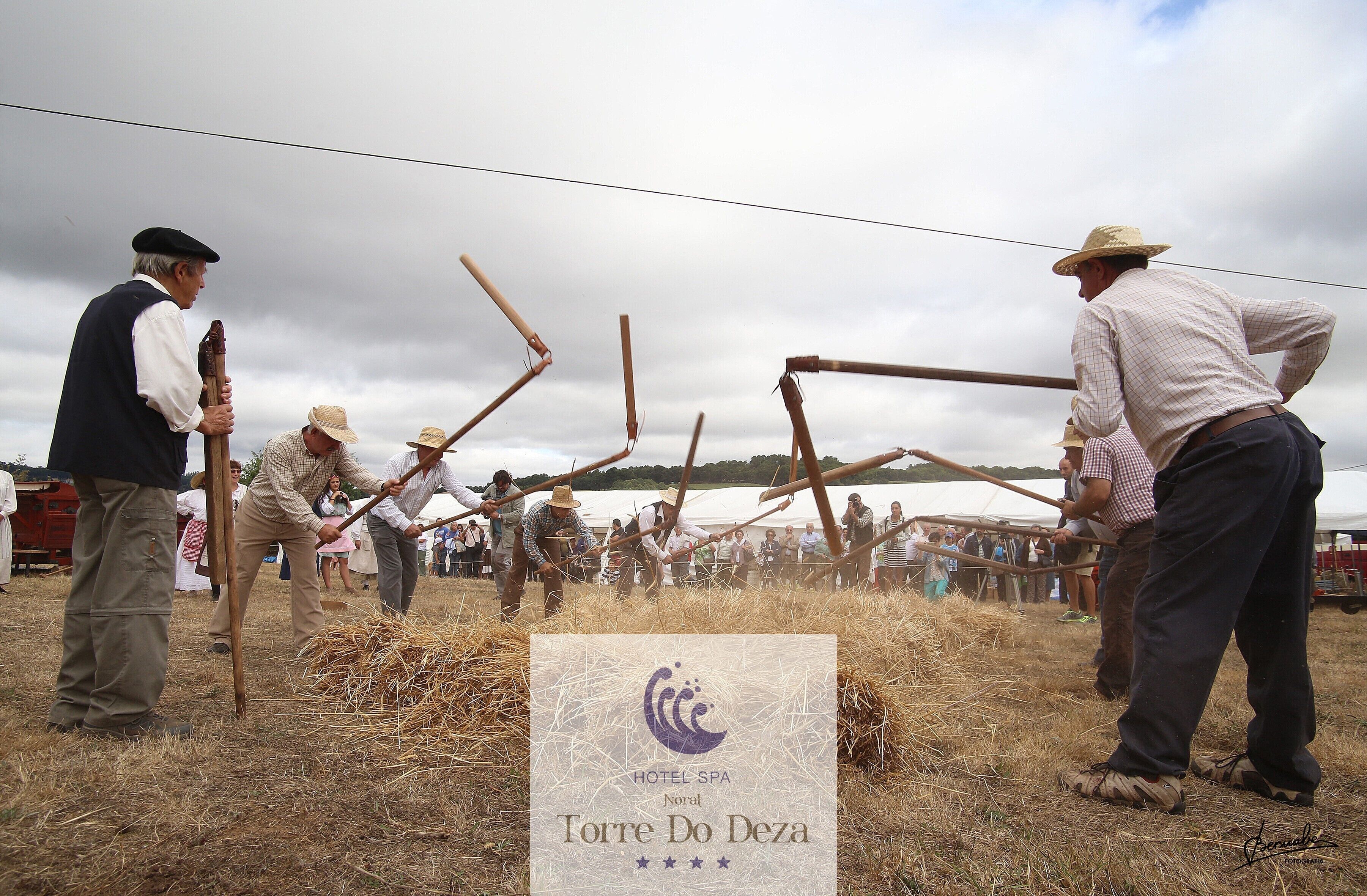 Un grupo de personas participa en una actividad tradicional, con un cartel de Hotel Spa Torre Do Deza al frente.