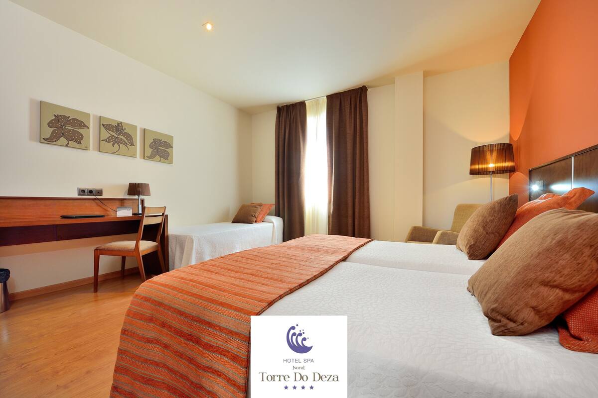 Una habitación de hotel con cama, escritorio, silla y ventana.