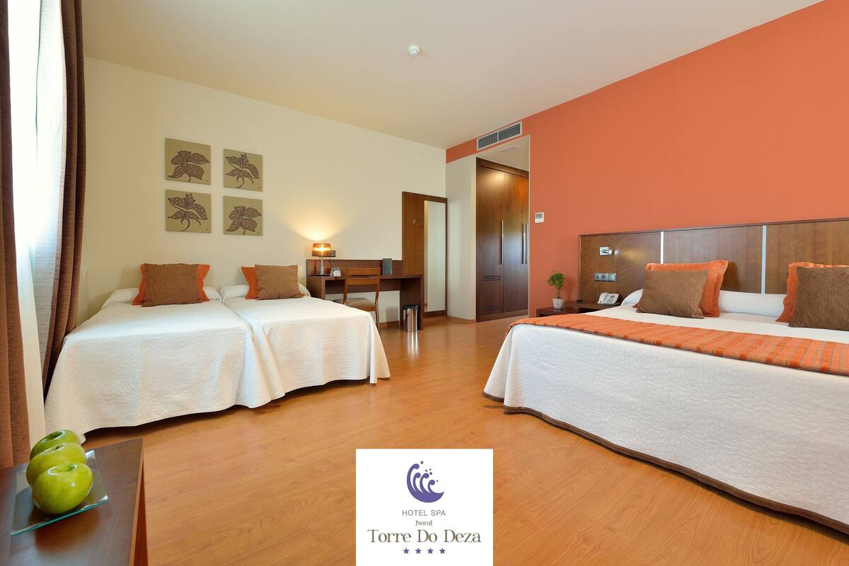 Habitación de hotel con dos camas, un escritorio, una silla y una mesita con manzanas.