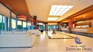 A spacious lobby with a reception desk, seating area, and large windows offering views of the cityscape. - Hotel Spa Norat Torre do Deza (Lalin)