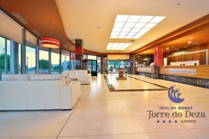 A spacious lobby with a reception desk, seating area, and large windows offering views of the cityscape.