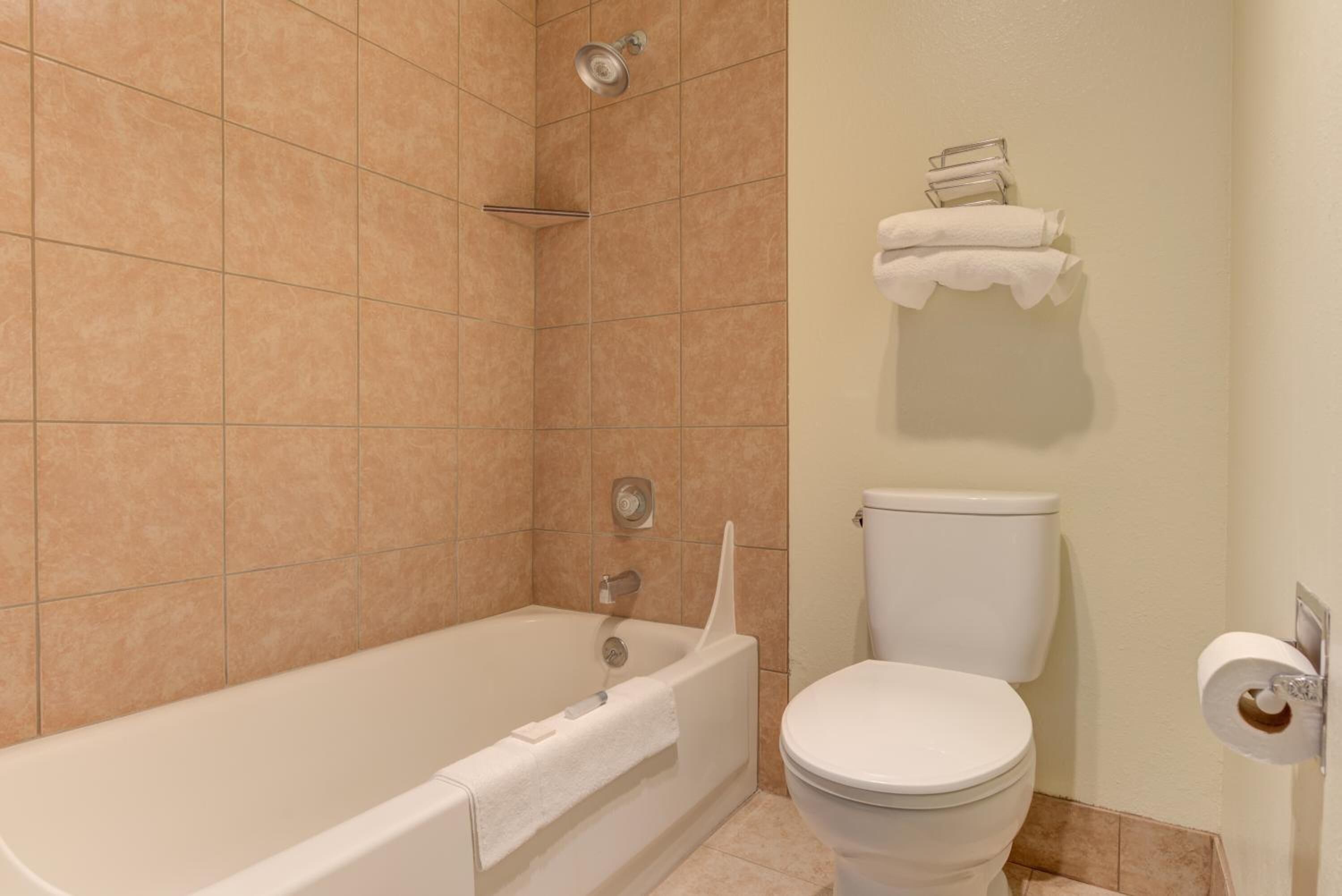 Un baño con bañera, inodoro y toallero.