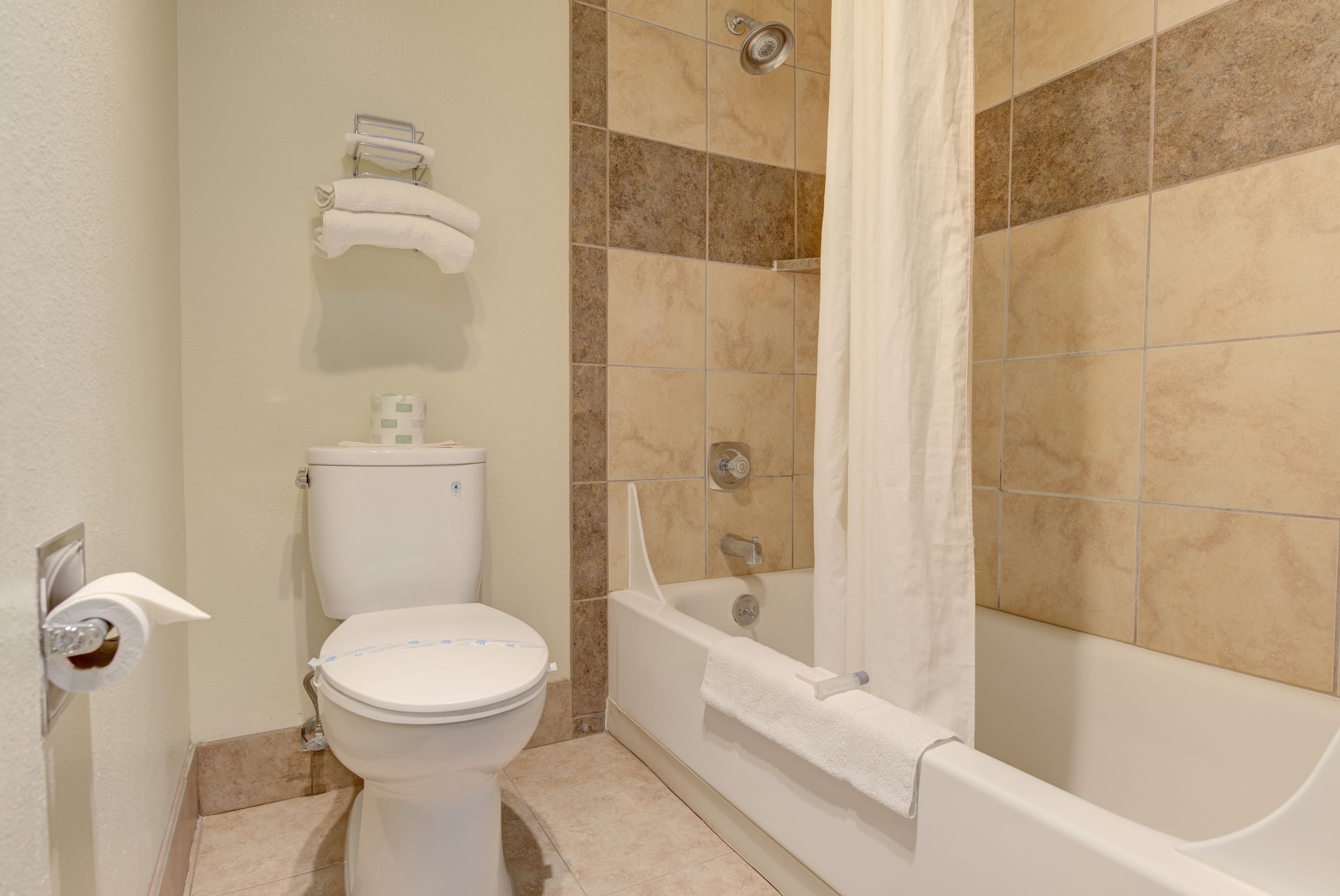 Un baño con inodoro, bañera y cortina de ducha.