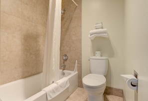 A bathroom with a bathtub, toilet, and shower curtain.