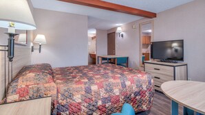 Habitación de hotel con cama, escritorio, televisor y baño a la vista.