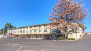 A multi-story motel with a parking lot in front.