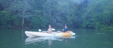 A couple in a kayak on a calm river surrounded by dense greenery.