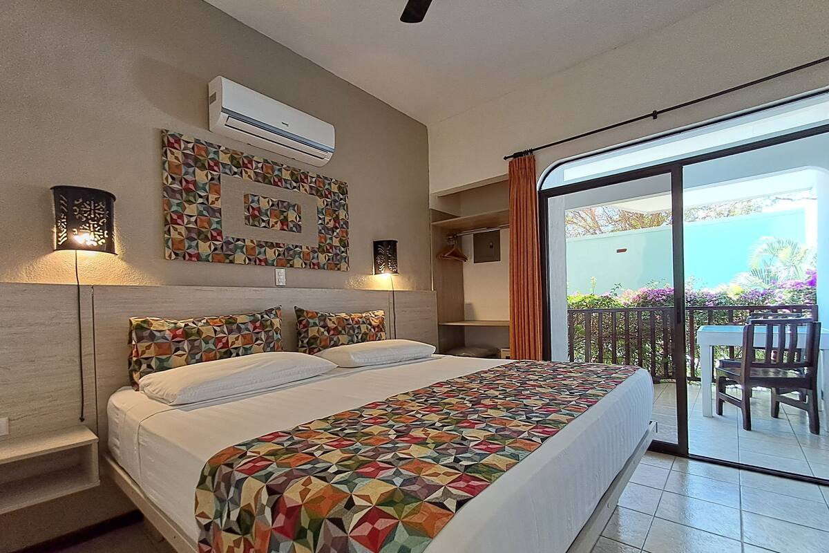 Una habitación de hotel con cama, balcón y vistas, aire acondicionado y decoración mural estampada.