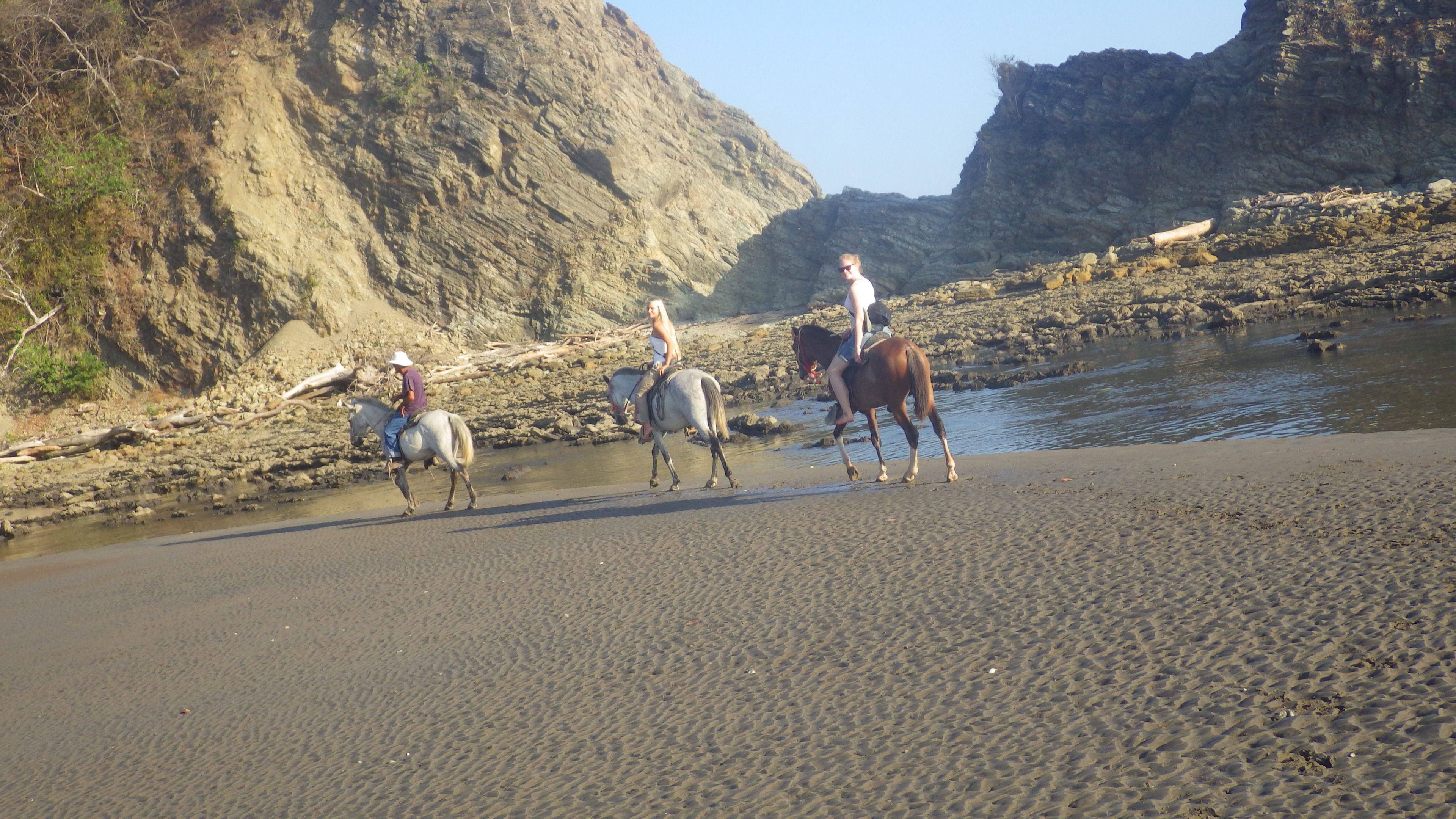A beach with horses and riders.