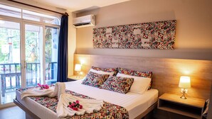 Ein Hotelzimmer mit einem großen Bett, zwei Nachttischen mit Lampen, einer Wandklimaanlage und einer Glastür zum Außenbereich.