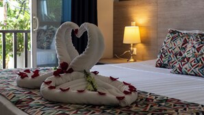 Ein Hotelzimmer mit einem Bett, dekoriert mit einer Schwantenschnitz aus Handtüchern, Rosenblättern und einer kleinen Blumenkomposition.