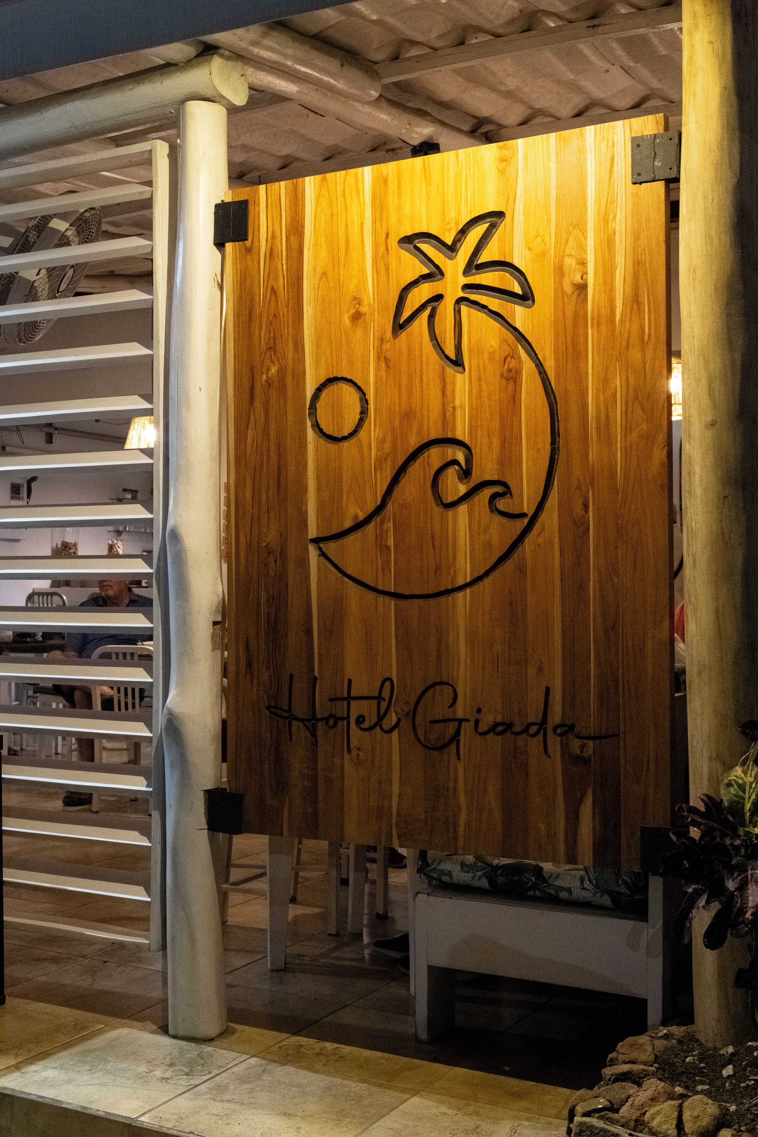 A wooden sign with a palm tree and wave design, and the text "Hotel Giada".