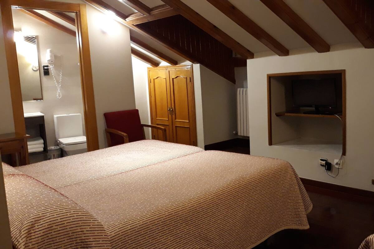 Un dormitorio con una cama, una silla, un armario y una estantería.