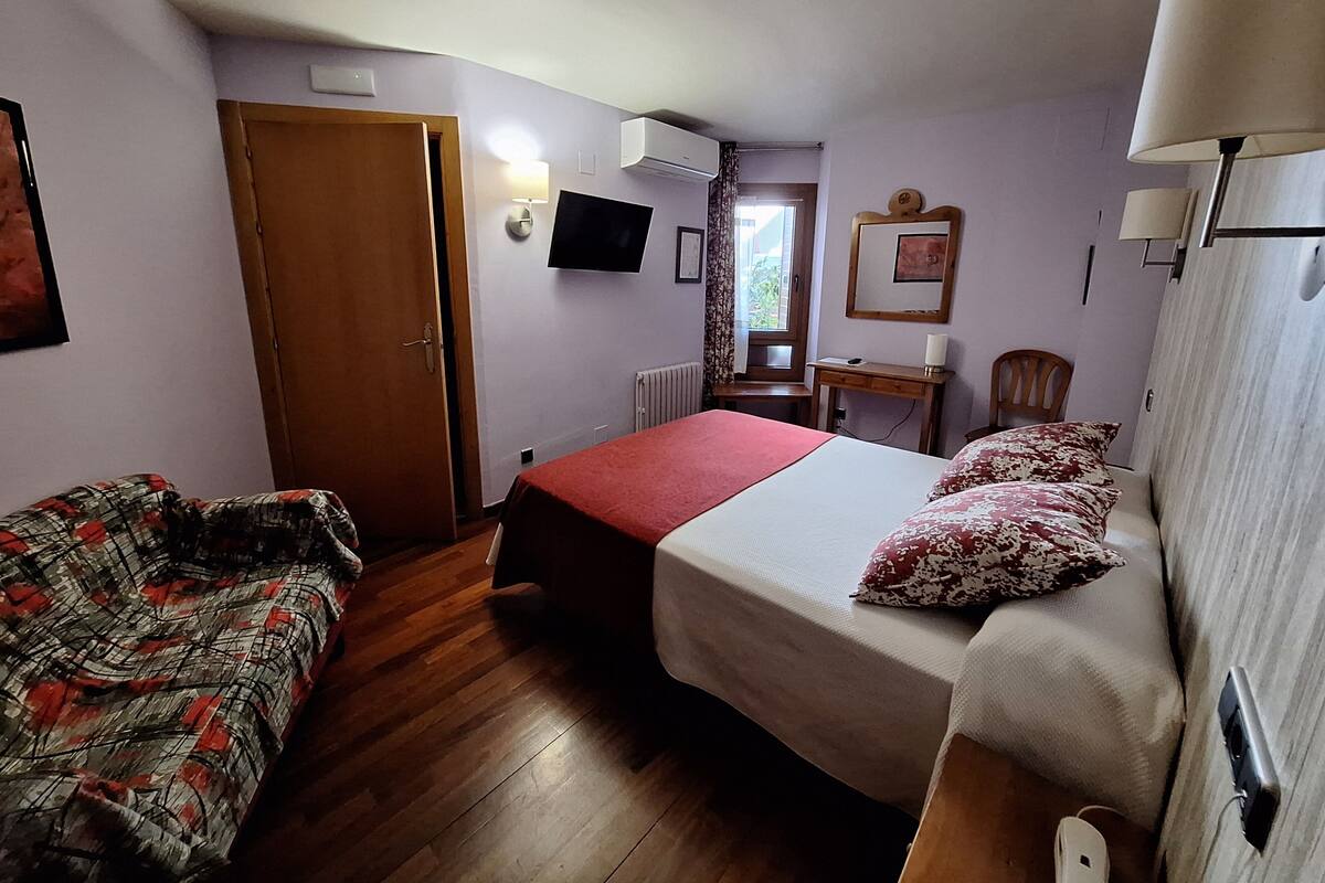 Una habitación con cama, sofá, escritorio y televisión.