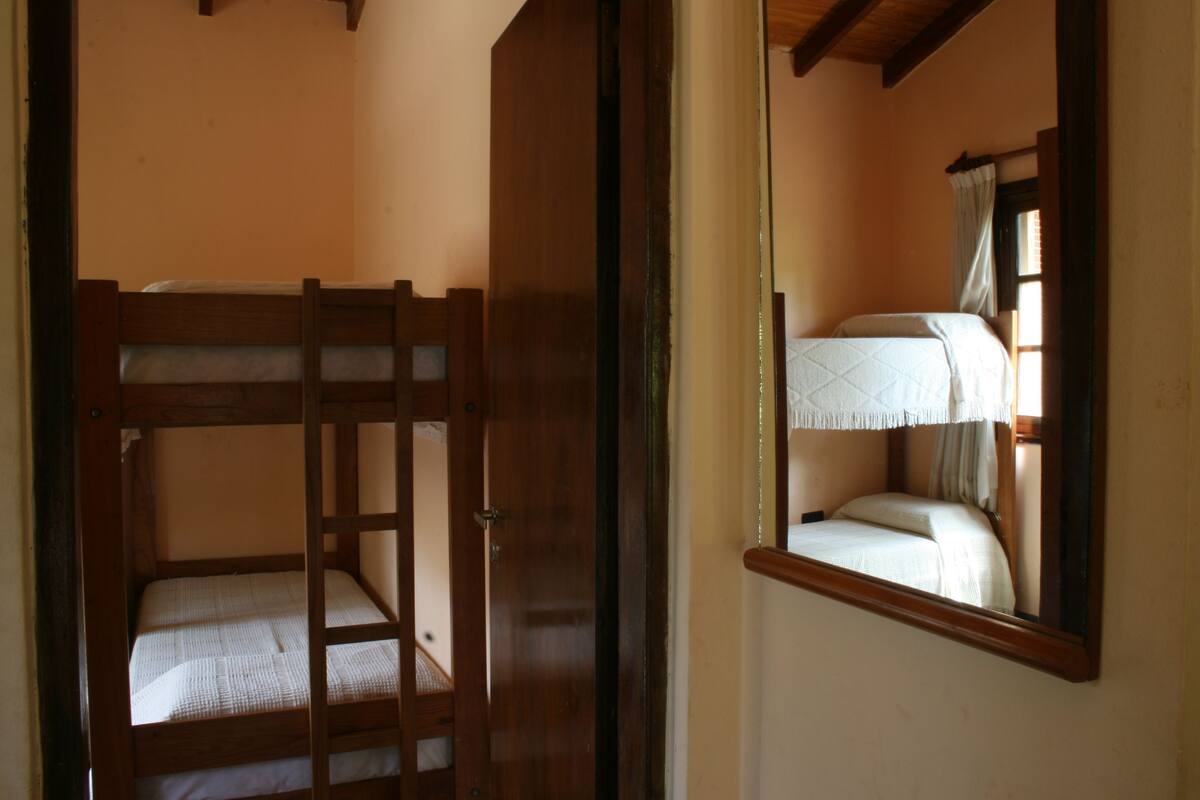 Une chambre avec un lit superposé et un miroir qui reflète une partie de la pièce.