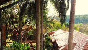 A view of a rustic building with a tiled roof, surrounded by lush greenery and palm trees. - Pirayu Lodge Resort (Puerto Iguazú)