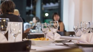 A restaurant setting with tables set for dining, including plates, cutlery, and wine glasses. - Pirayu Lodge Resort (Puerto Iguazú)