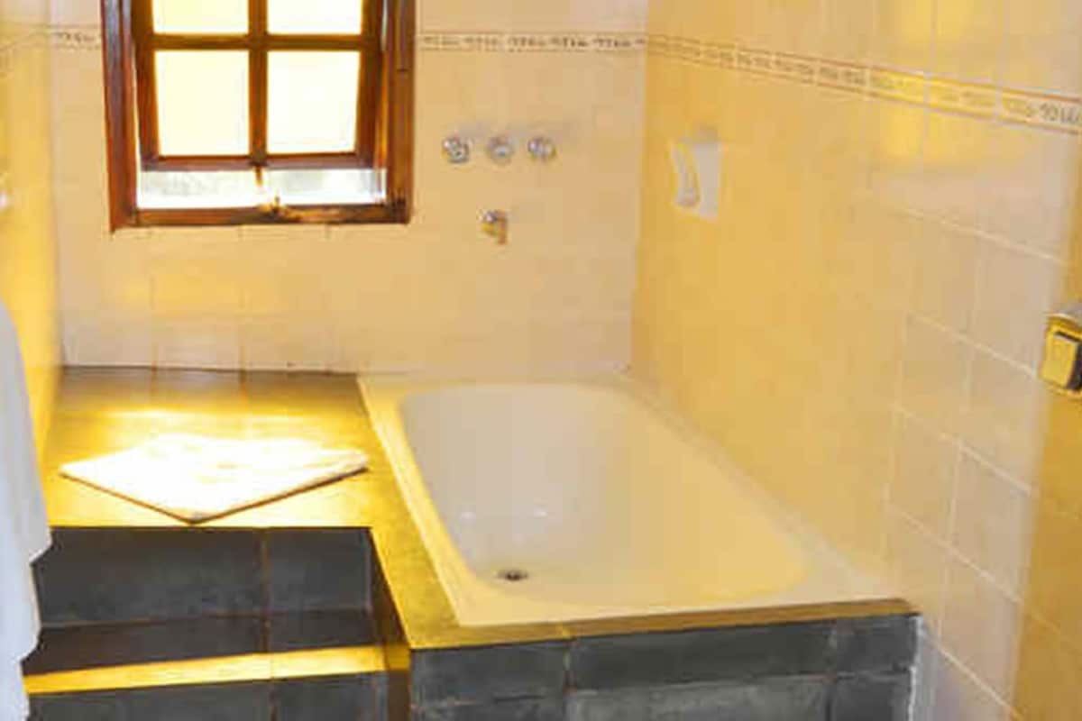 A bathroom with a bathtub, a window, and a towel rack.