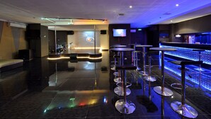 A modern bar area with a reflective floor, bar stools, and a neon-lit bar counter. - Gino Feruci Kebonjati (Bandung)
