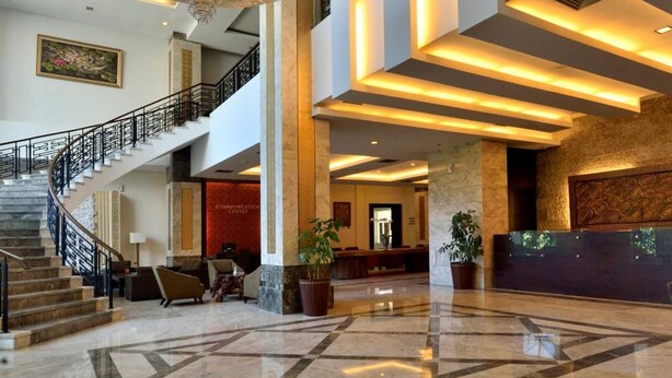 A spacious lobby with a grand chandelier, a staircase, and a reception desk. - Gino Feruci Kebonjati (Bandung)