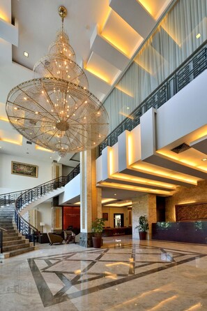 A spacious lobby with a grand chandelier, a staircase, and a reception desk. - Gino Feruci Kebonjati (Bandung)