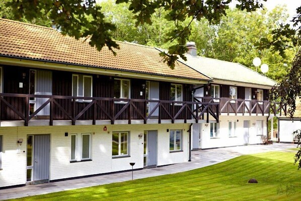 A two-story building with a balcony, a flat roof, and a well-maintained lawn.