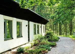A white building with multiple windows and a gravel path leading to it.