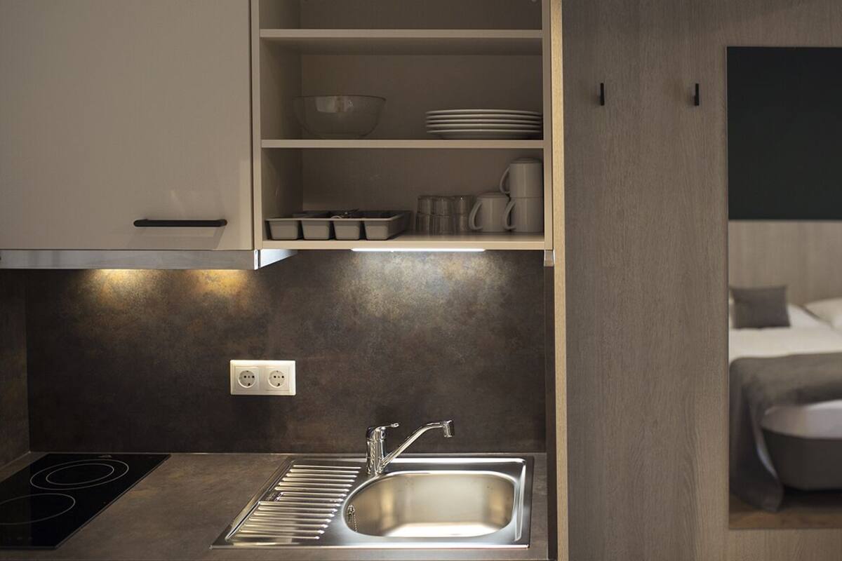 A modern kitchen with a built-in stove, a sink, and a countertop with storage cabinets.