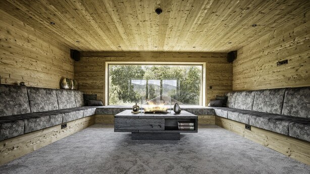 A room with a large window, a central fireplace, and a sofa along the walls.