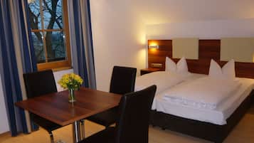 Ein Hotelzimmer mit einem hölzernen Bett, einem Nachttisch, einem Schreibtisch mit Stühlen und einem Fenster mit Vorhängen.