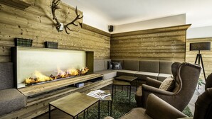 A modern living room with a fireplace, wooden wall paneling, a sofa, and a television.